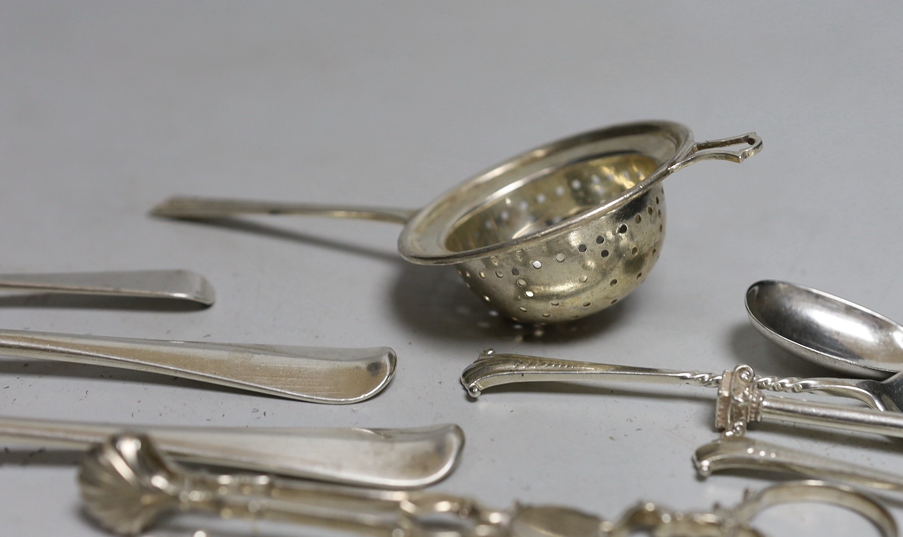 A silver tea strainer and a small collection of assorted 20th century and earlier silver cutlery, various dates and makers, including a pair of mid 18th century sugar nips, 9.7oz.